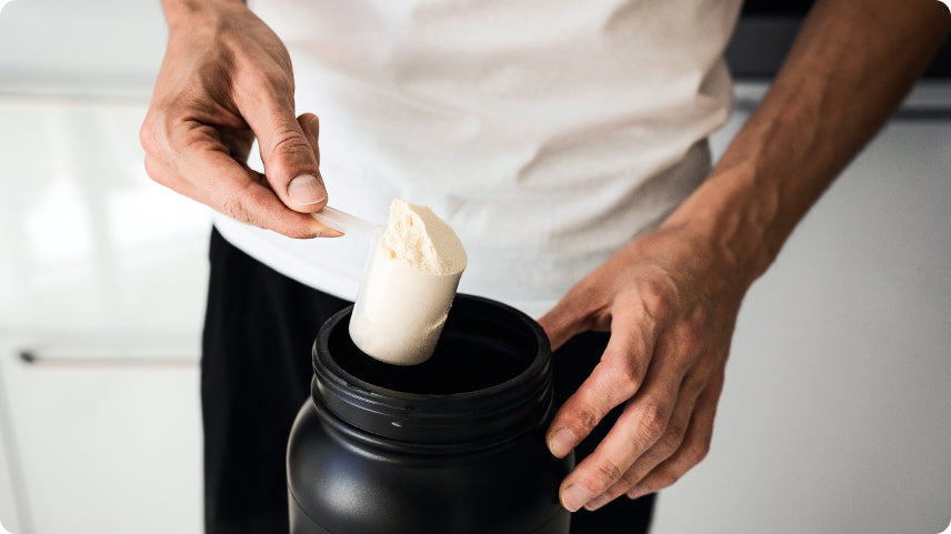 Person measuring whey protein powder from a supplement container